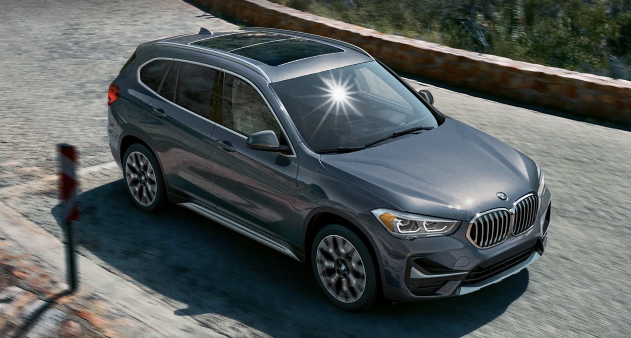 2022 BMW X1 in gray driving down the road at a high speed.