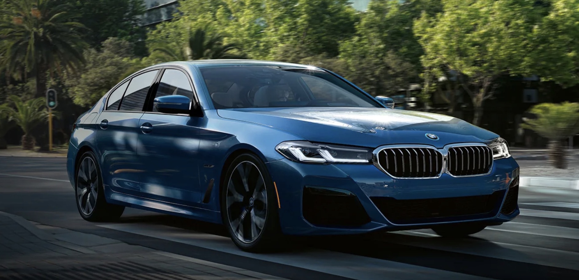 Blue 2022 BMW 5 Series driving along the topical landscape of Florida.