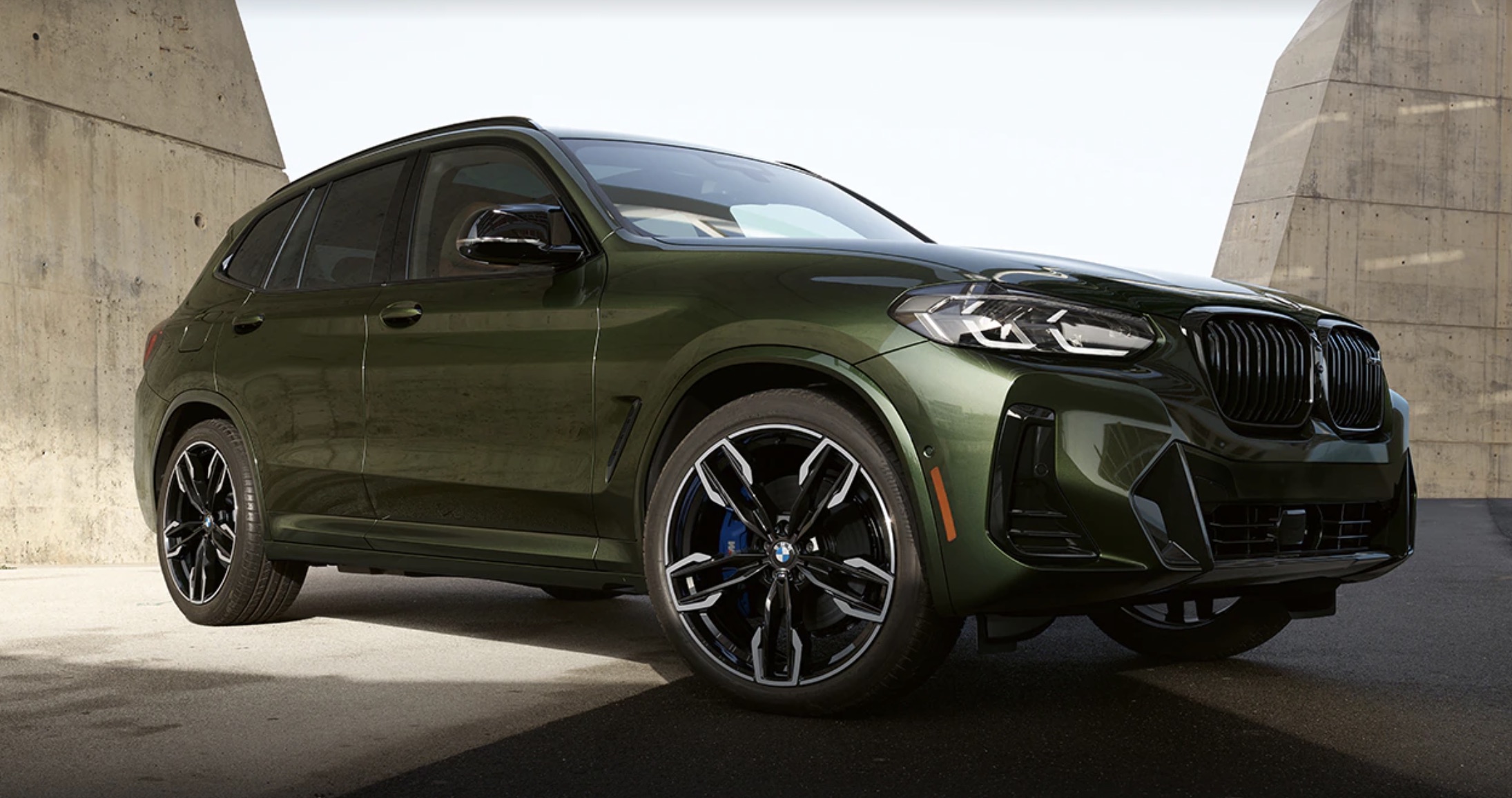 The 2022 BMW X3 in green parked inside of a parking garage with the light shining down in the background.