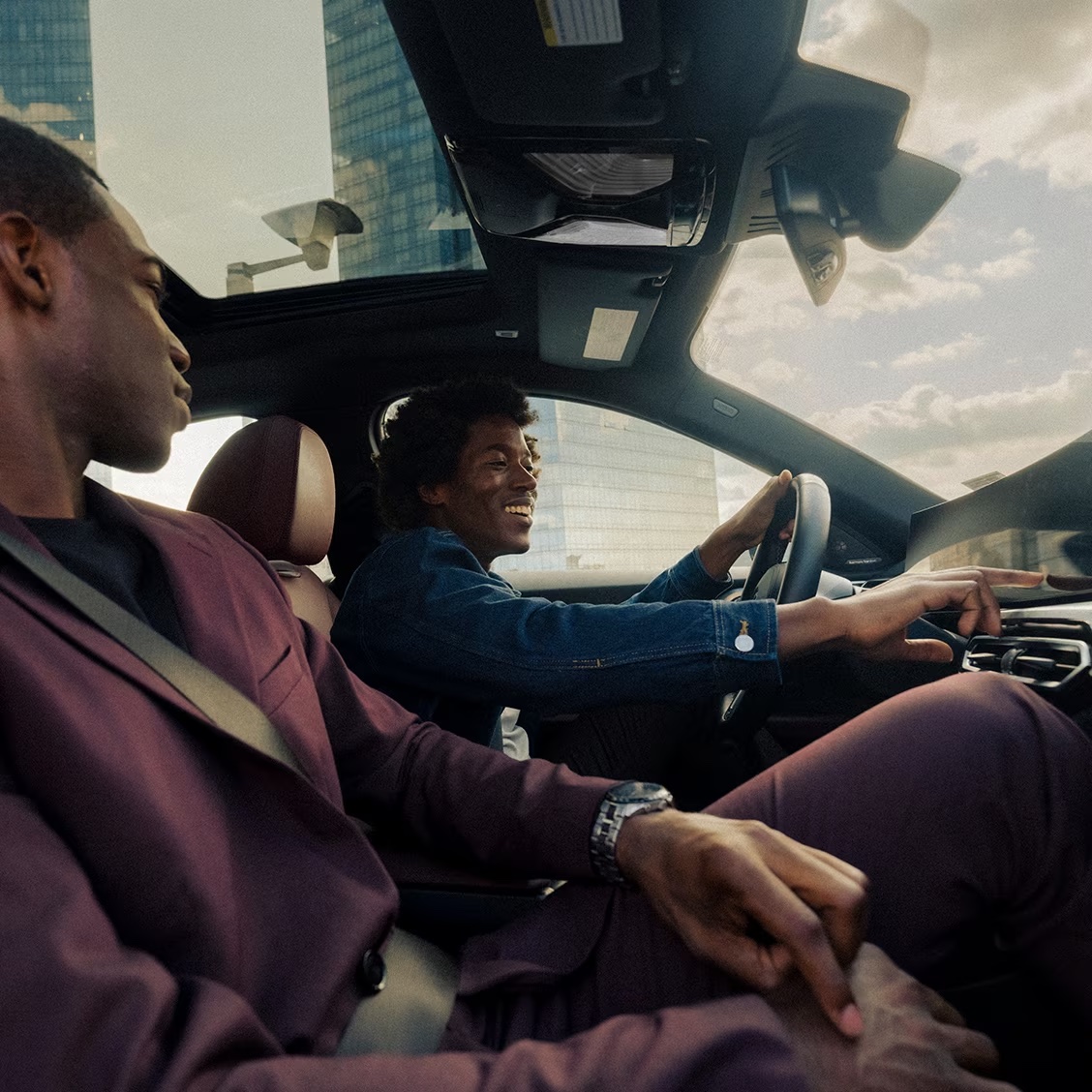 Two men in the front of a BMW adjusting the controls